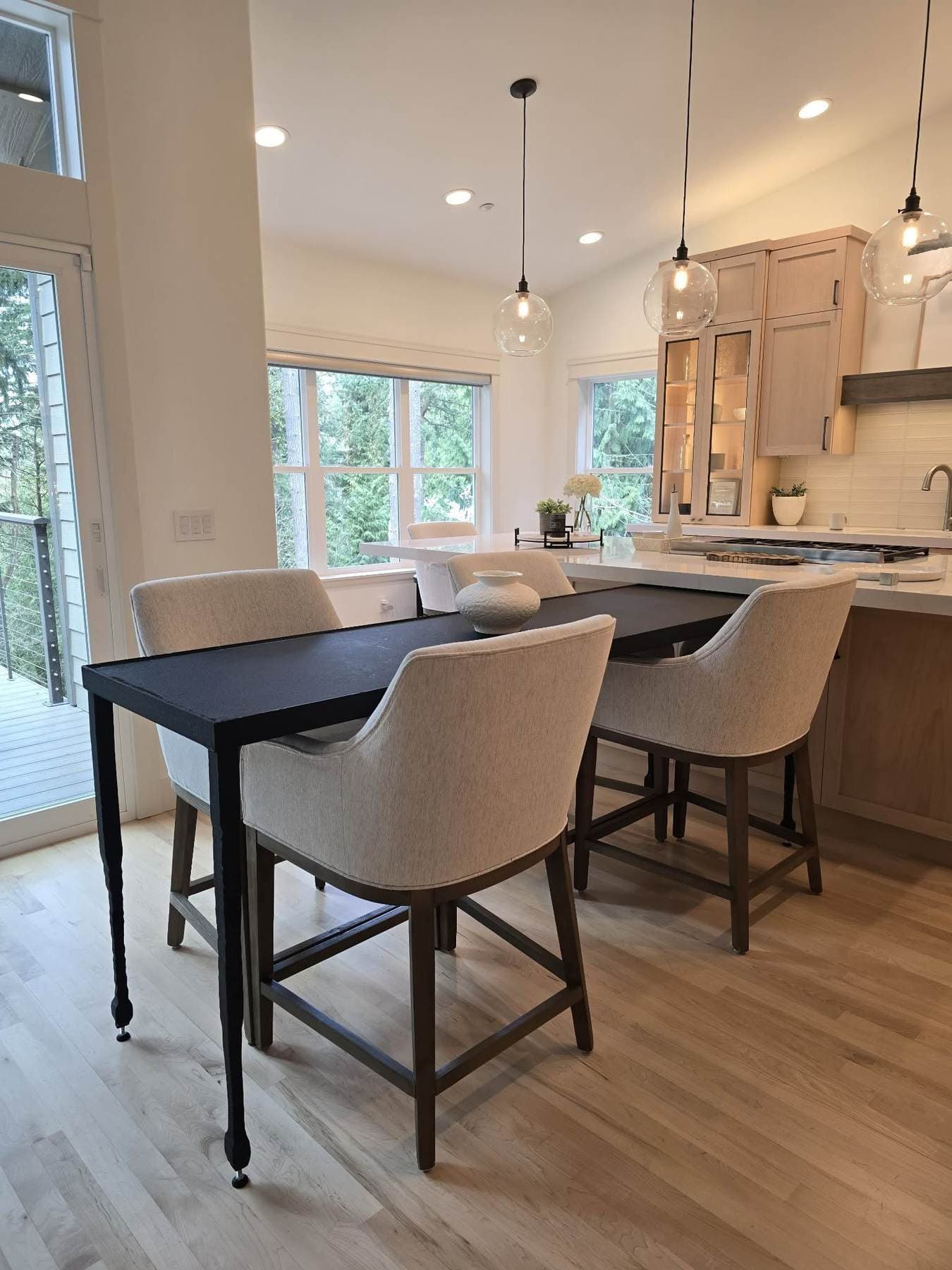 Kitchen island extended into a peninsula table, supported by a single tapered, hand-textured blackened-steel leg.